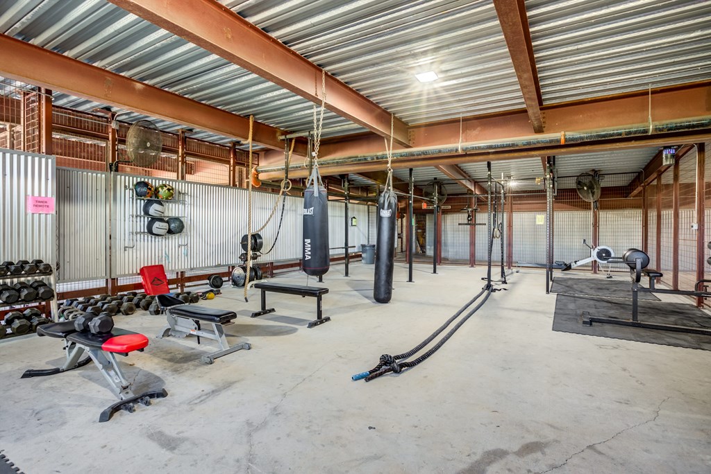 A gym with a variety of equipment including weights and benches.