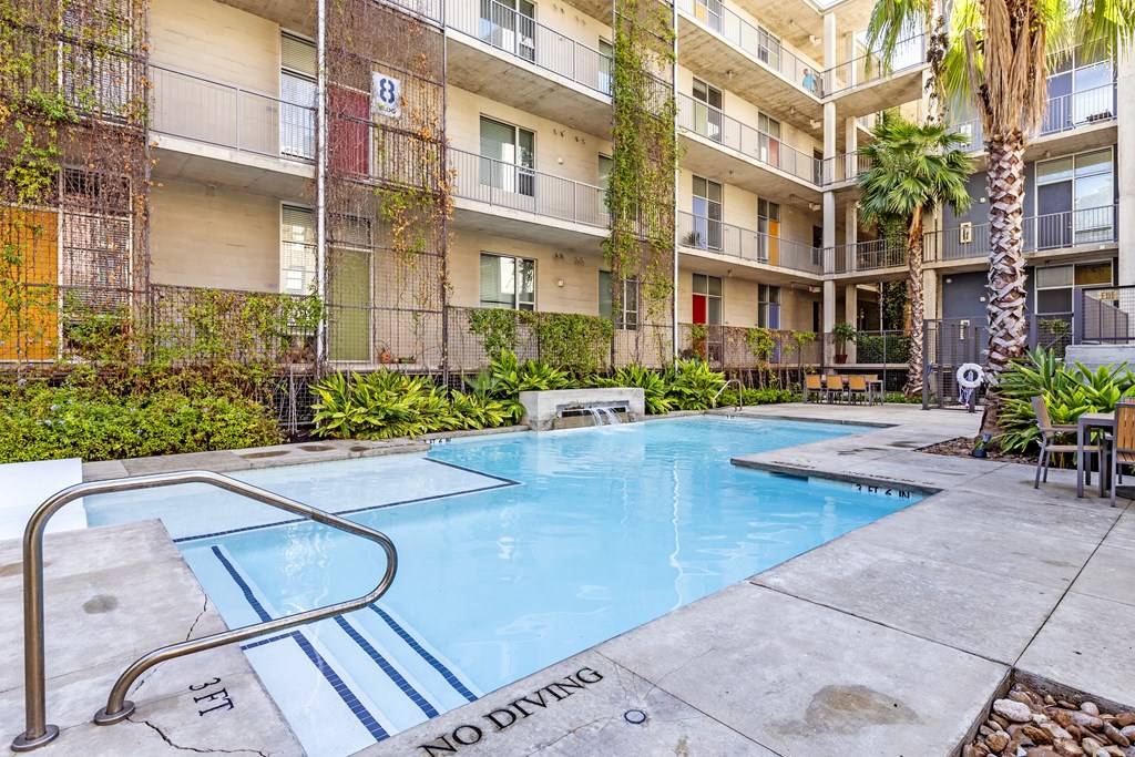 A pool surrounded by apartment buildings with a "No Diving" sign.