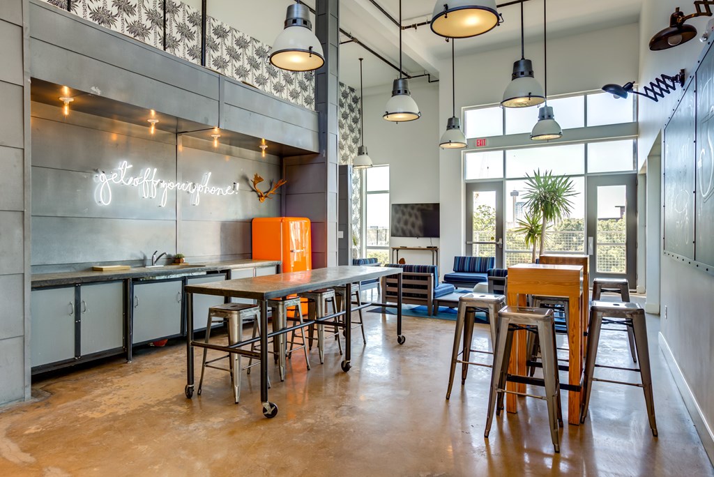 A modern kitchen with a bar area and a neon sign that says "Coffee & Tea".