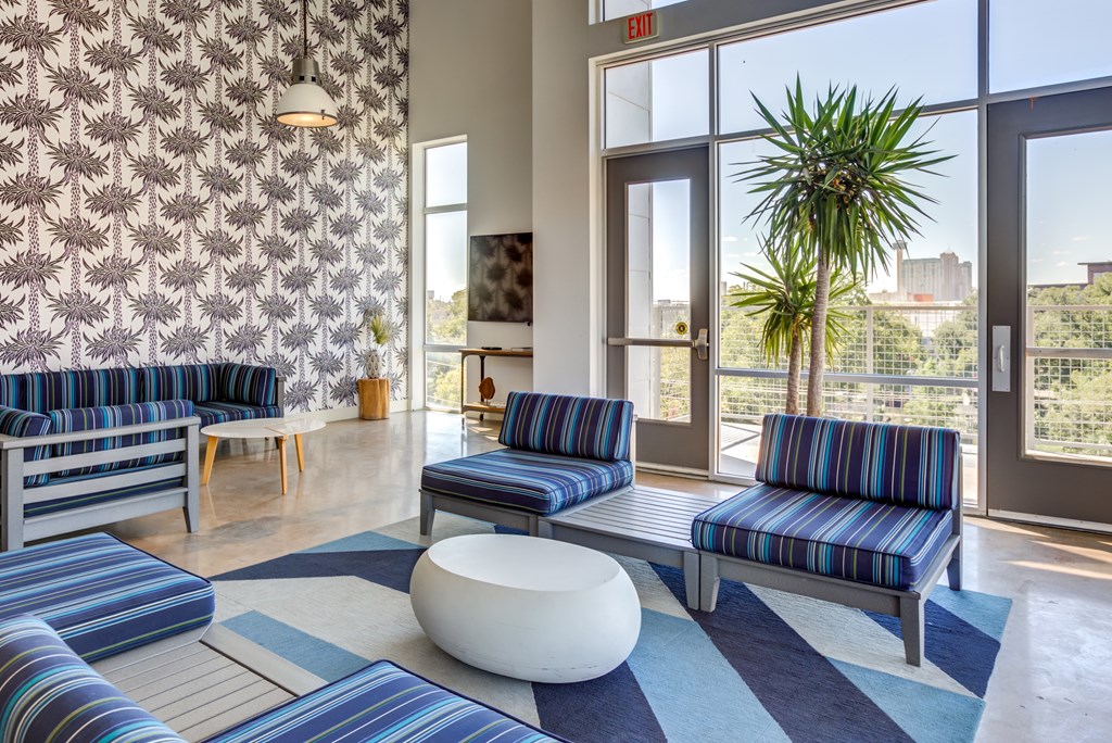 A room with blue and white striped couches and a white ottoman.