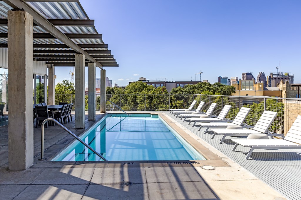 A pool surrounded by sun loungers and a metal roof.
