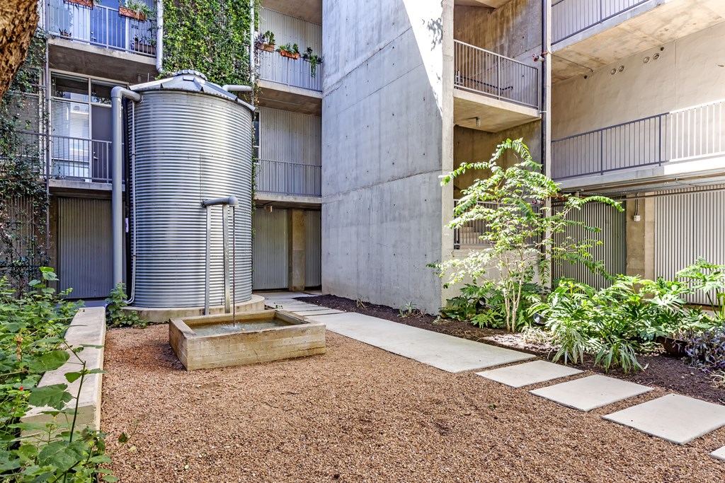 A courtyard with a water tank and a small tree.