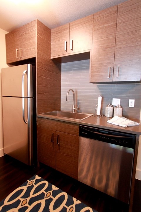 A modern kitchen with a stainless steel refrigerator and dishwasher.