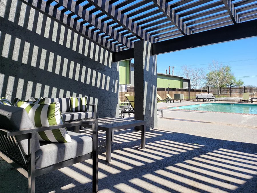 a patio with chairs and a table next to a pool