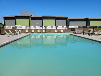 a swimming pool with chairs around it and a building in the background