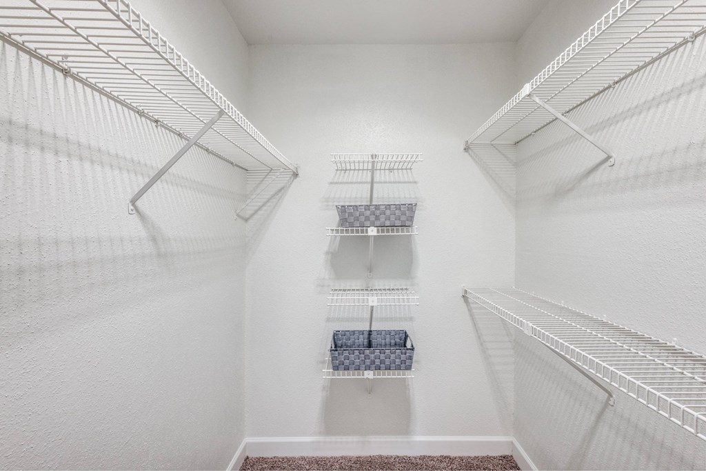A white walk-in closet with shelves and a bench.