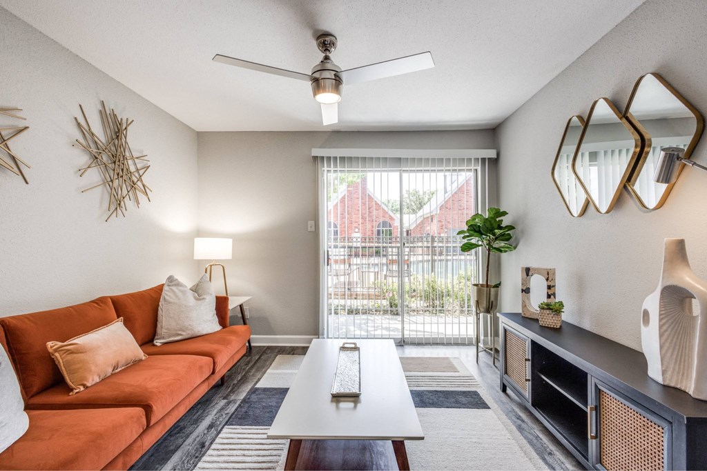 A living room with a red sofa, a white coffee table, and a ceiling fan.