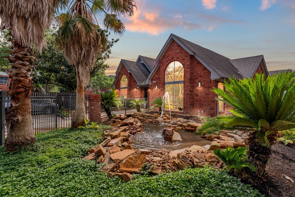 A house with a red brick exterior and a waterfall in the front yard.