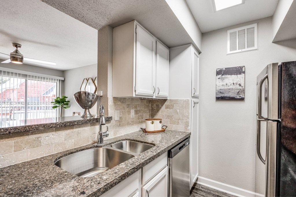 A kitchen with a stainless steel refrigerator and a granite countertop.