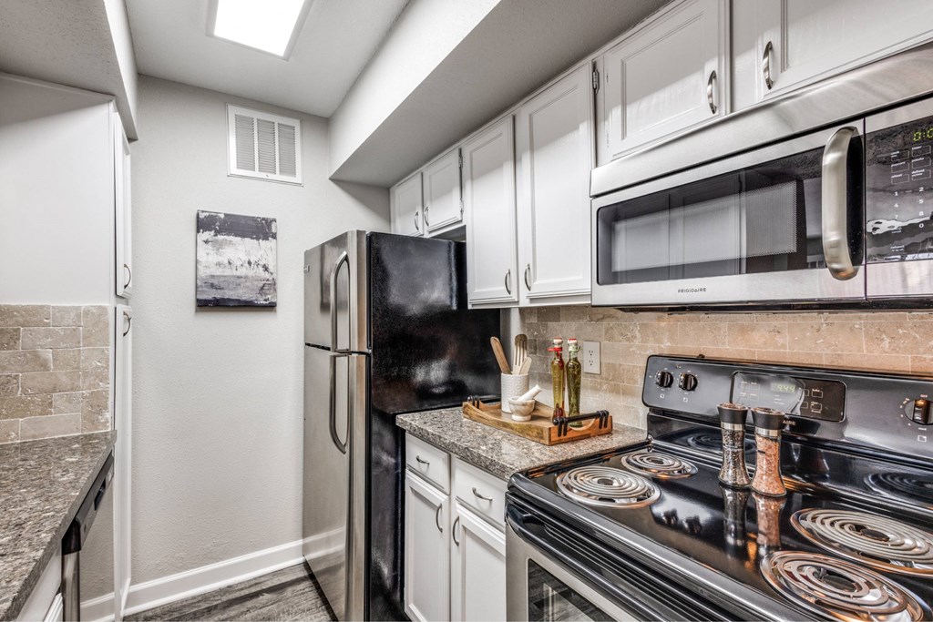A kitchen with black appliances and white cabinets.