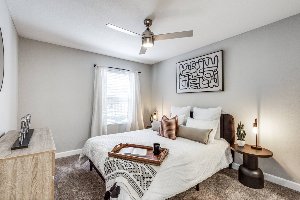 A bedroom with a bed, nightstand, and a ceiling fan.