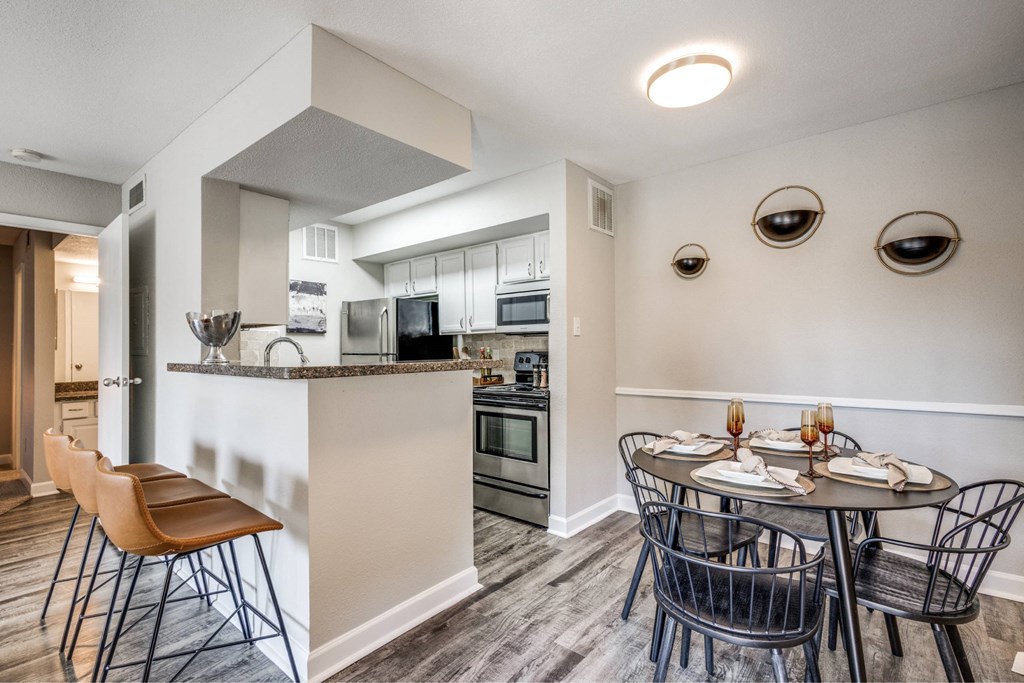 A modern kitchen with a dining table set for two.