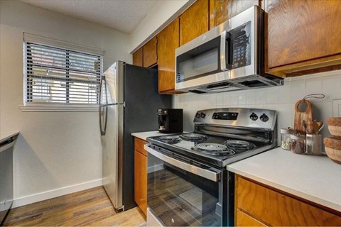 Kitchen with stainless steel appliances and wood cabinets at The Courtyard Apartments, Texas, 75044