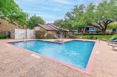 Resort style pool with patio seating area at The Courtyard Apartments, Garland, Texas