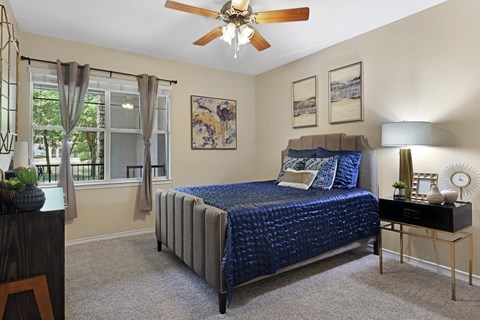 A bedroom with a bed, nightstand, and window.