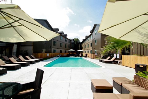A pool surrounded by sun loungers and umbrellas.