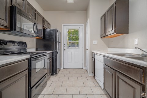 A kitchen with dark brown cabinets and a white door.