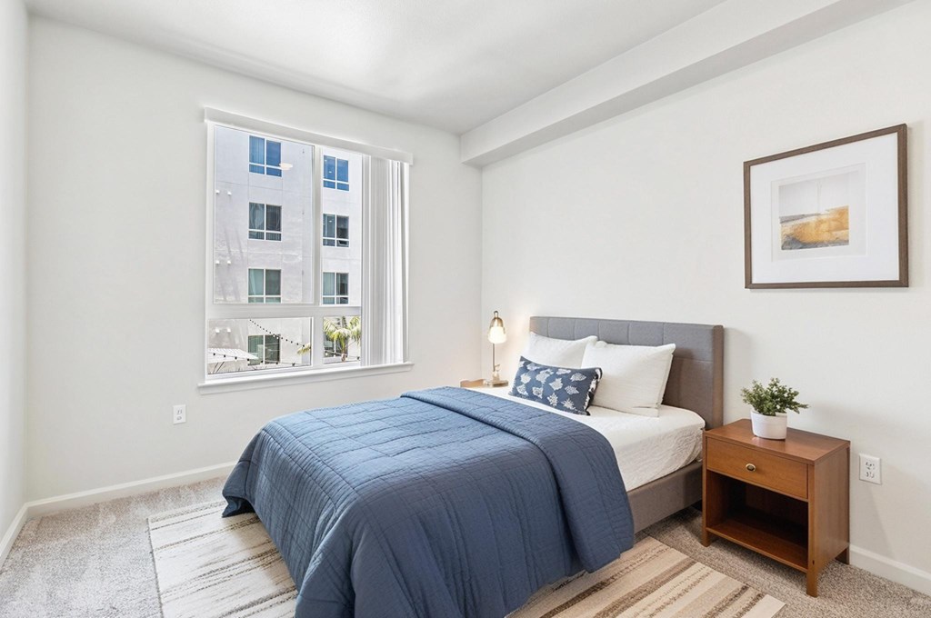 A bedroom with a large bed and a window overlooking a building.