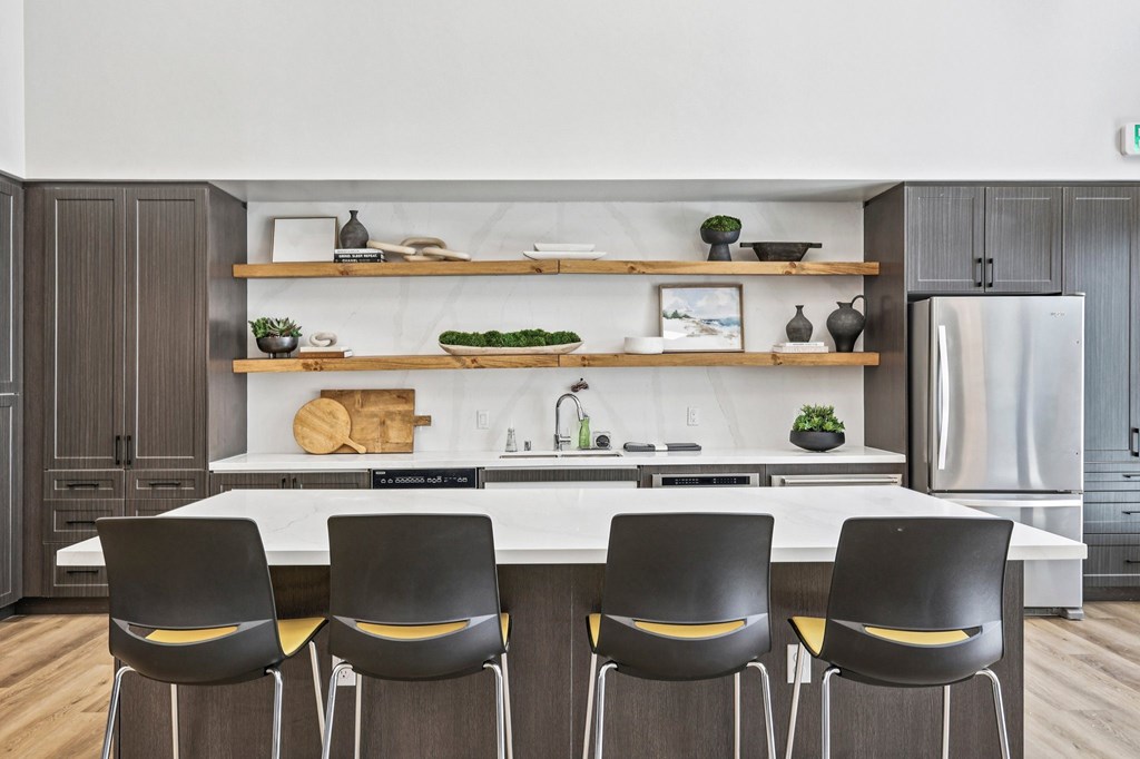 A modern kitchen with a white countertop and black chairs.