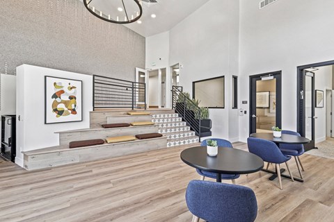 A modern living room with a staircase and a painting on the wall.