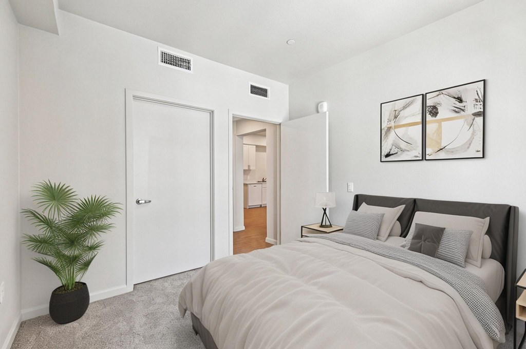 A bedroom with a large bed and a potted plant.