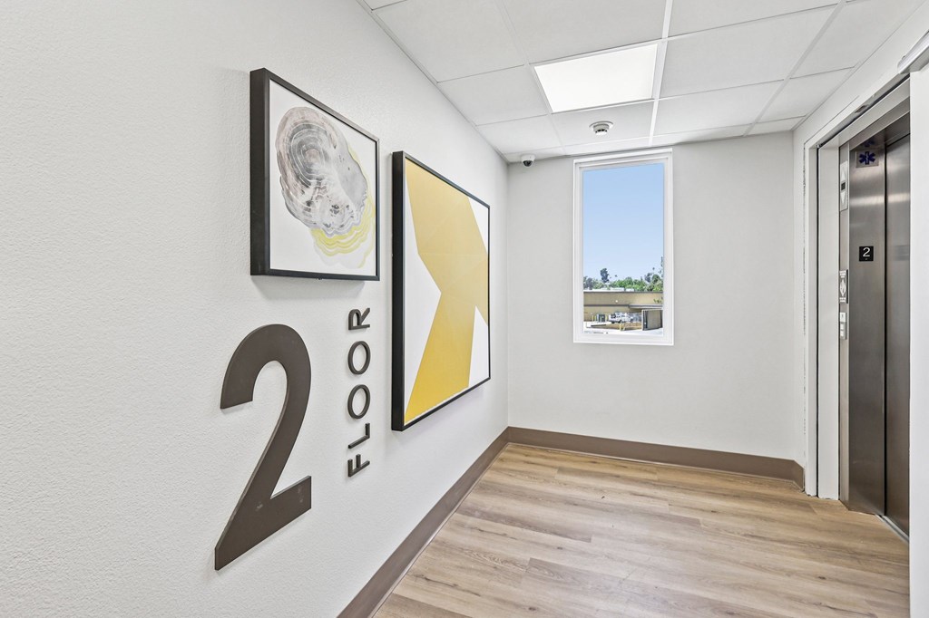 A hallway with a 2 on the wall and a picture of a window on the wall.