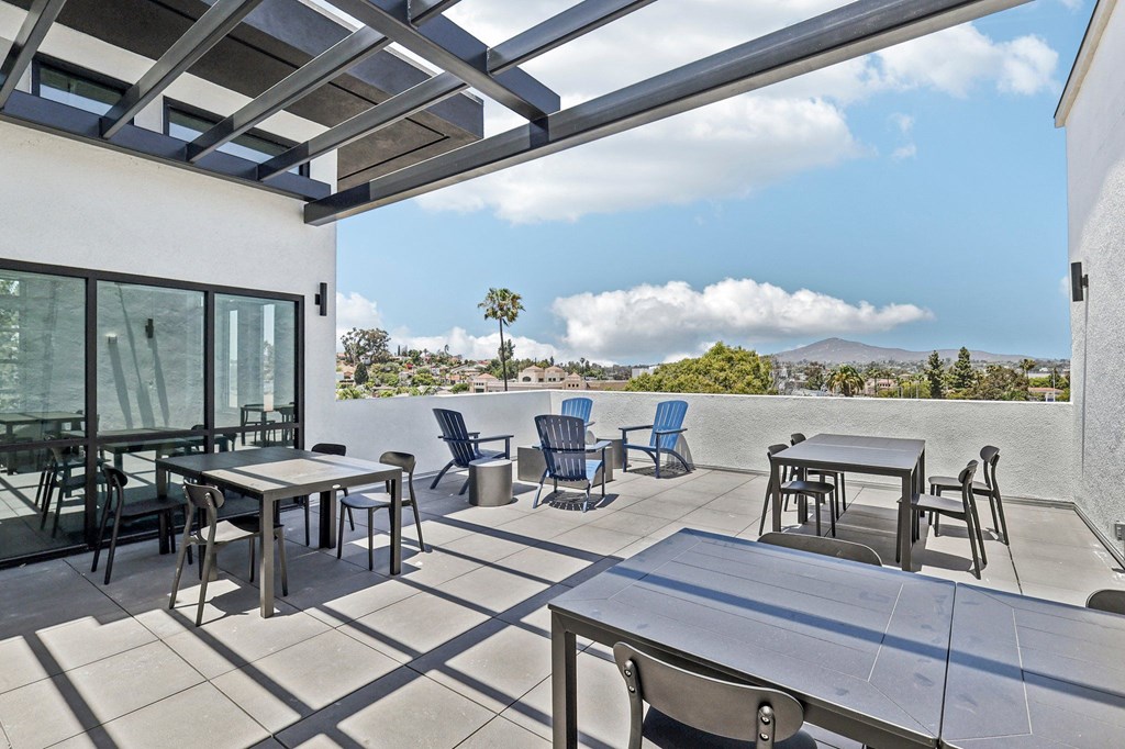 A patio with a table and chairs overlooking a mountain.
