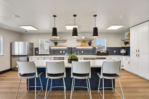 A modern kitchen with white chairs and a blue tablecloth.