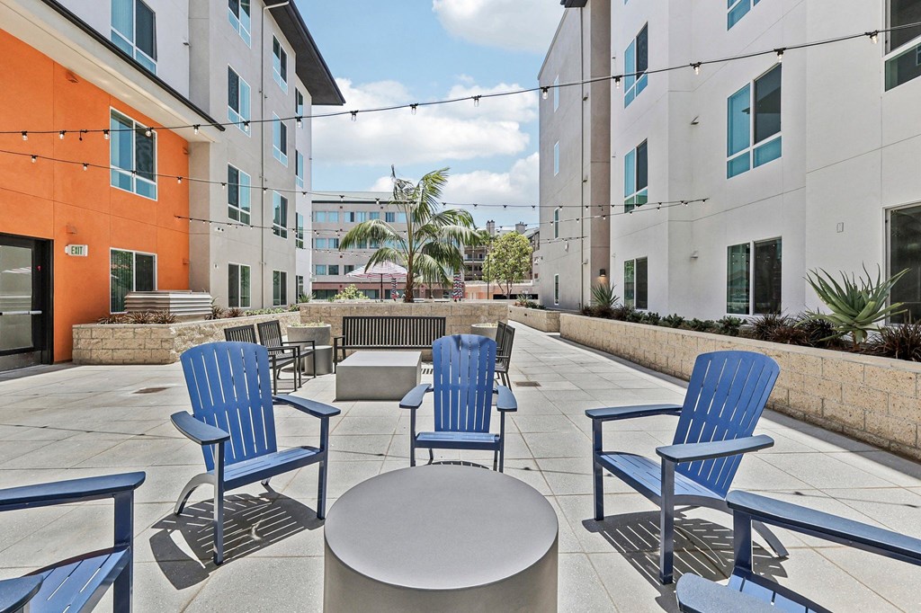 Four blue chairs and a table are on a patio.