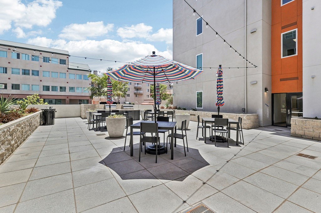 A patio with a table and chairs under a striped umbrella.