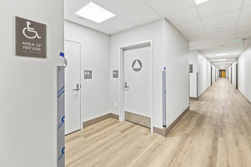 A hallway with doors and a sign that says "Area of Refuge".