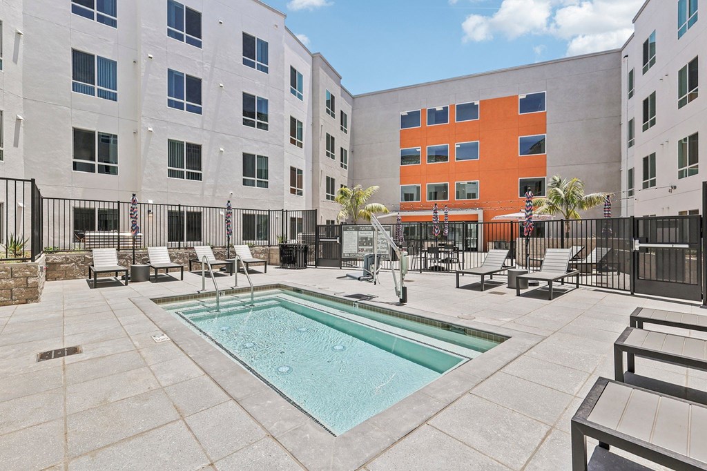 A pool surrounded by chairs and a fence.