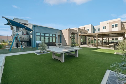 Outdoor recreation area with playground and ping pong at The Crawford Apartments, California