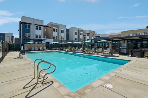 A swimming pool surrounded by a fence and chairs.