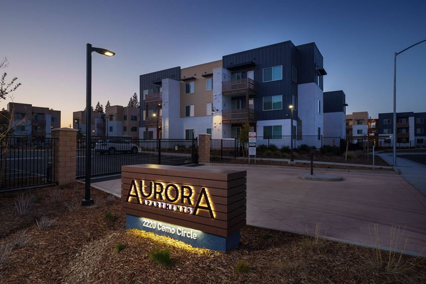 Aurora Apartments monument sign with community in the background