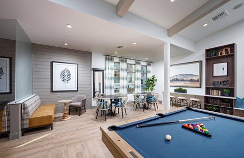 Rancho Cordova, CA Pet-Friendly Garden-Style Apartments - Aurora - Clubhouse with Couch, Armchair, Coffee Table, Tables and Chairs, Bookshelf, and Billiards Table.
