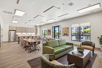 a lounge area with couches chairs and tables and a kitchen