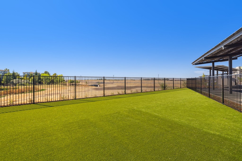 fenced off dog park with a fence and faux turf