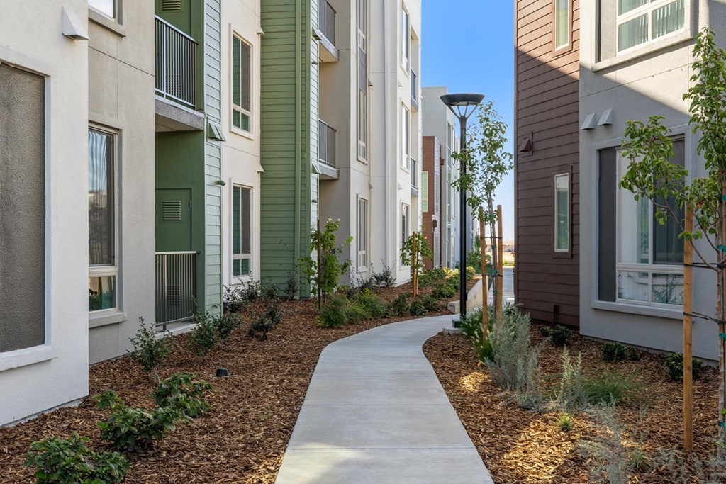 a sidewalk in front of a row of apartment buildings