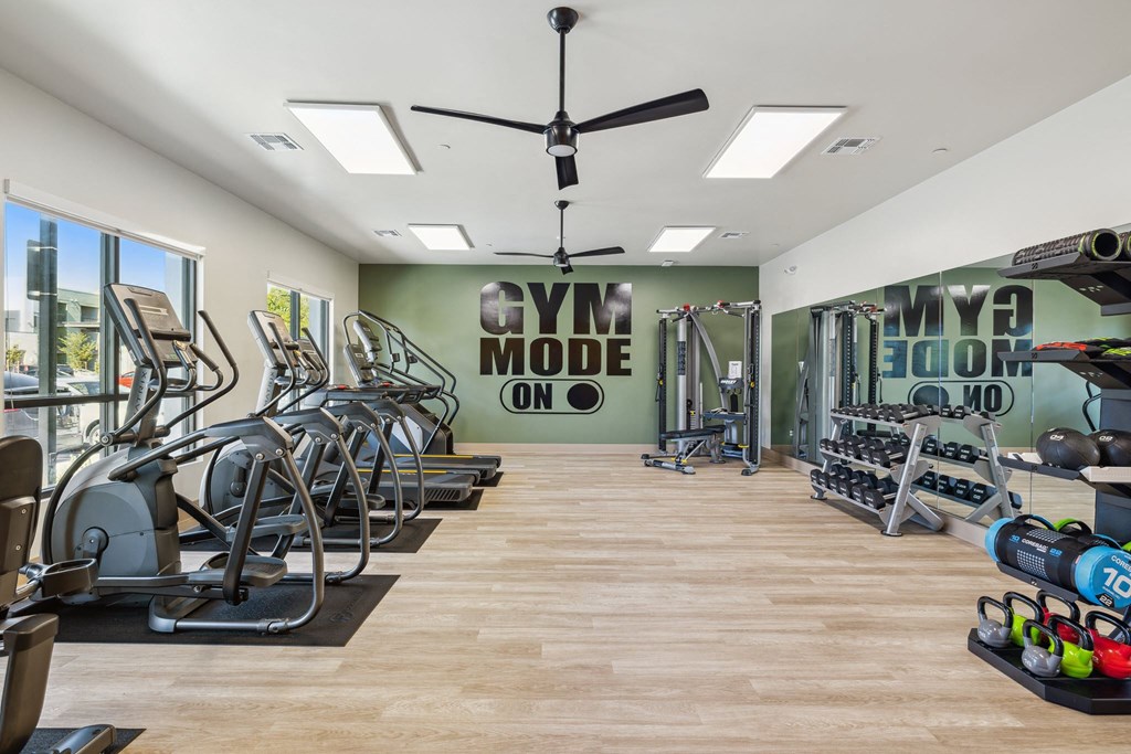 a gym with cardio machines and weights on the floor and a wall with a quote