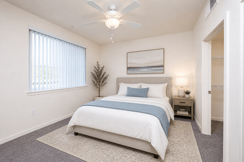 Serene bedroom with upholstered bed and vertical blinds at Terracina at Lancaster | Affordable Apartments, Lancaster, California