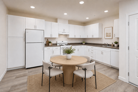 A kitchen with white cabinets and a round table with four chairs.
