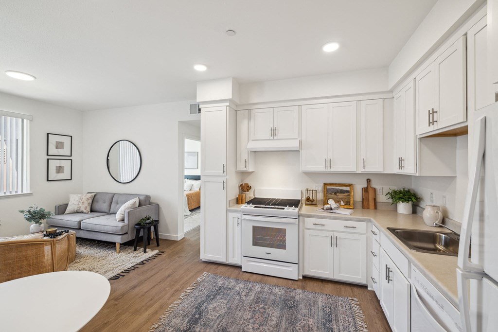 a white kitchen with white cabinets and a living room with a couch