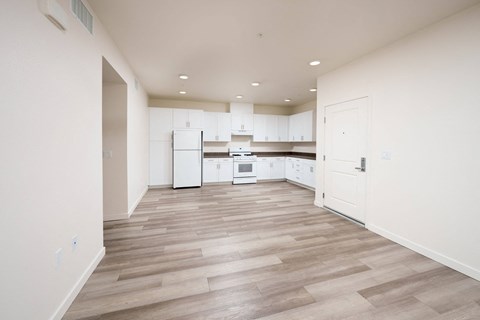 A kitchen with white appliances and wooden floors.