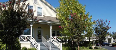 A house with a porch and a tree in front.