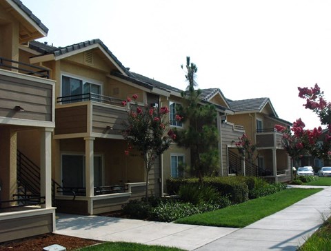 A row of houses with a sidewalk in front.