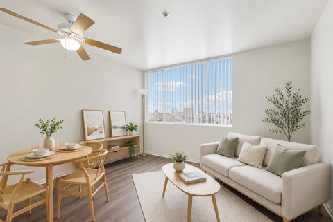 A living room with a couch, table, chairs, and a ceiling fan.