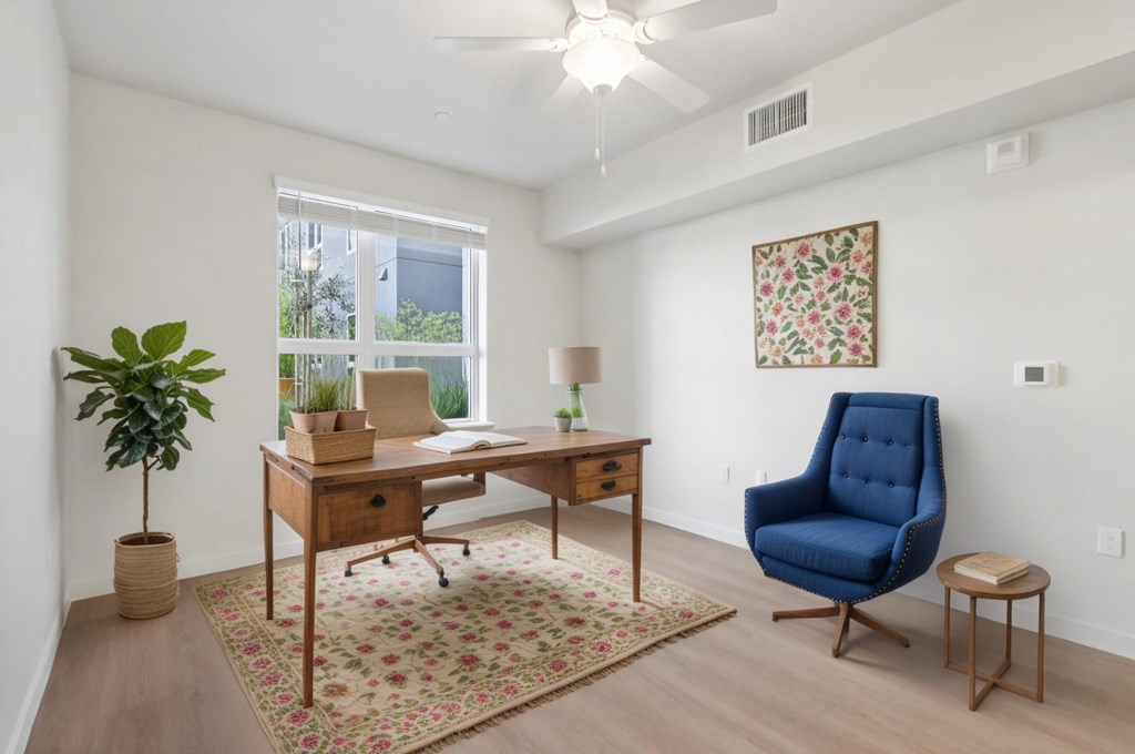 A room with a desk, chair, and potted plant.