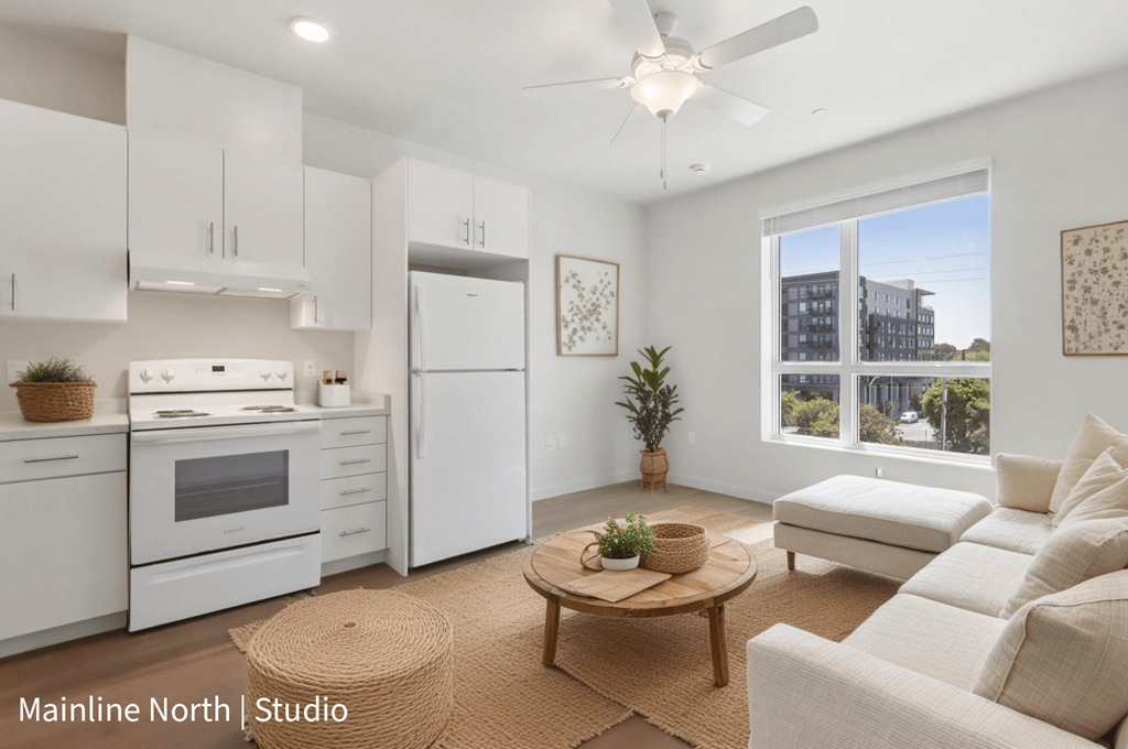 A well-lit studio apartment with a kitchen area and a living room.