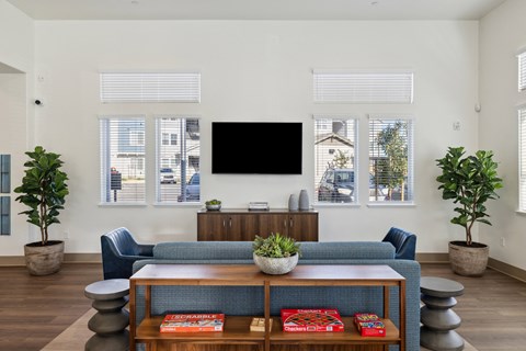 A living room with a blue couch and a flat screen TV mounted on the wall.